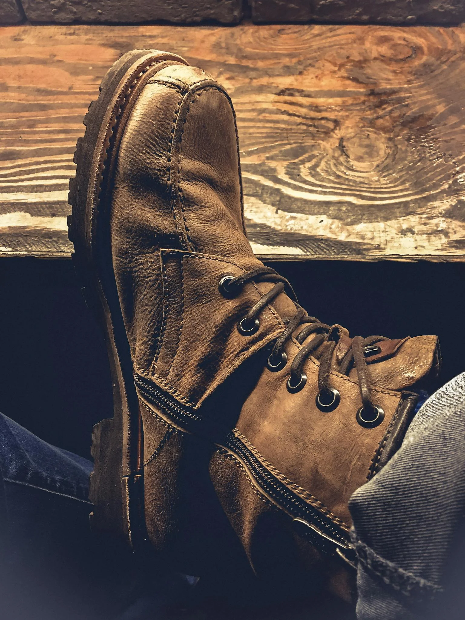 A close-up view of rugged brown leather boots resting on a wooden surface, showcasing vintage fashion.