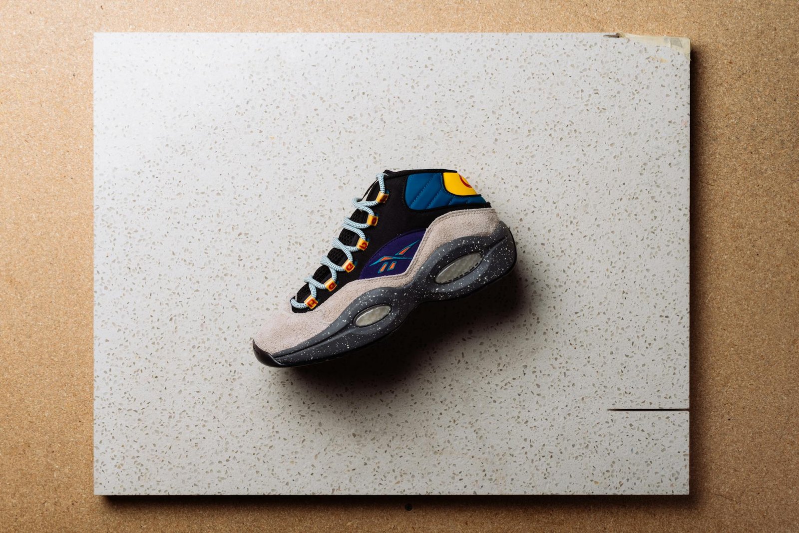 A vibrant Reebok sneaker displayed on a textured surface in an artistic composition.
