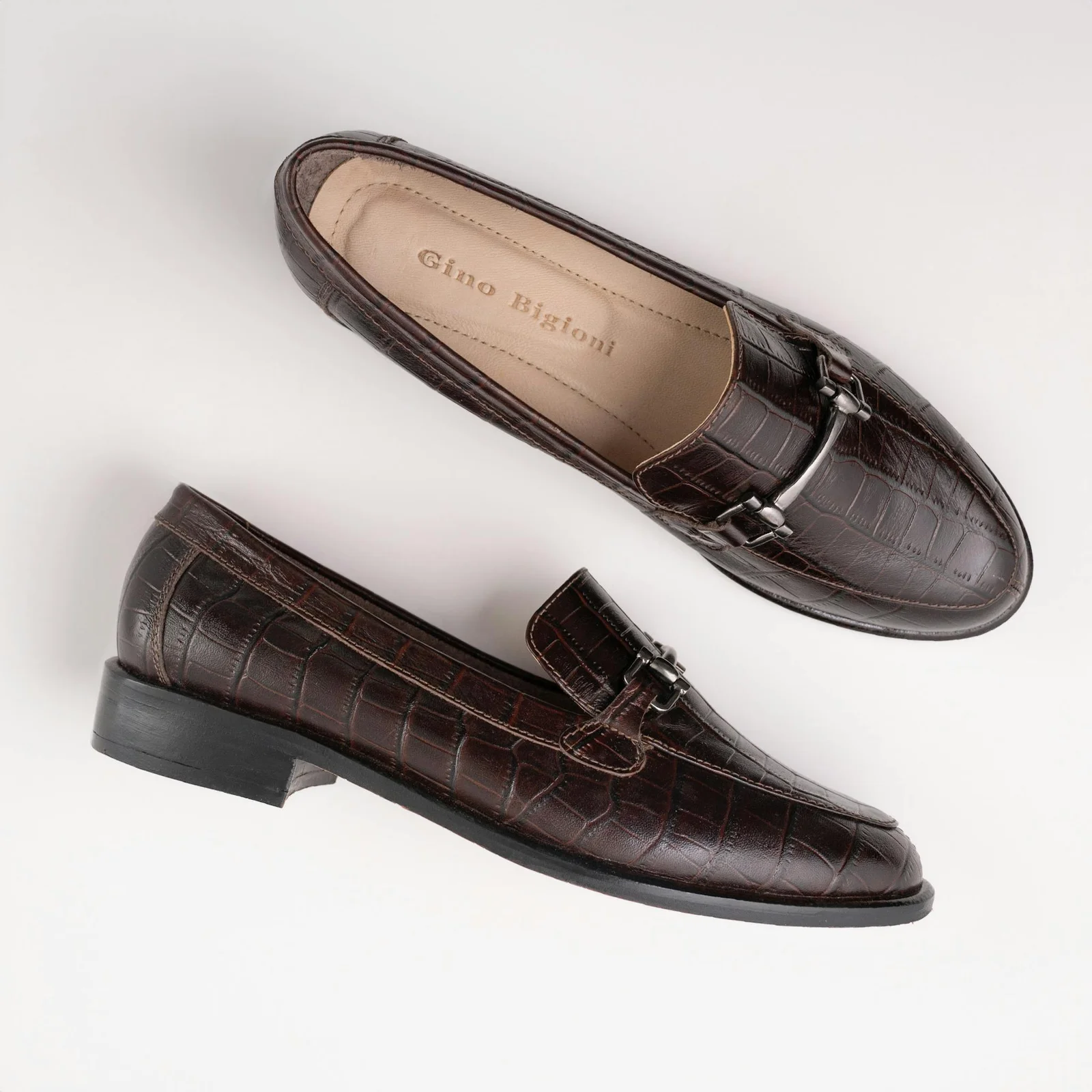 Stylish brown leather loafers with croc-embossed pattern on a white background.